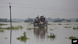 Flood-affected villagers travel on a boat in Gagalmari, in the northeastern Indian state of Assam, July 19, 2019. In the Indian state of Assam, officials said floodwaters have killed more than a dozen people and brought misery to 4.5 million. 