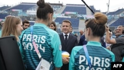 Rais wa Ufaransa Emmanuel Macron (kati) akizungumza na wanariadha wakati akitembelea eneo la uwanja wa mchezo"Stade Tour Eiffel" huko Champ-de-Mars mjini Paris, Ufaransa, 24 Julai 2024, kabla ya michezo ya Olimpiki Paris 2024 kuanza.