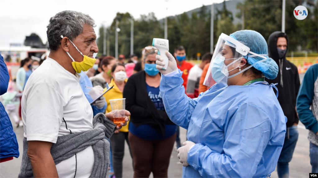 Una miembro del personal de salud de la Alcaldía de Chía controla la temperatura de los migrantes que esperaron en los buses. [Foto: Diego Huertas]