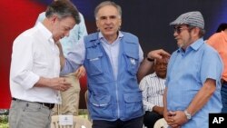 Jean Arnault, U.N. representative for the Colombian peace process, center, talks to Colombia's President Juan Manuel Santos, left, and Rodrigo Londono, the top commander of the Revolutionary Armed Forces of Colombia, FARC, during an act to commemorate the completion of the disarmament process of FARC rebels, in Buenavista, Colombia, Tuesday, June, 27, 2017. 