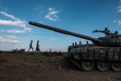 FILE - Youngsters walk next to an abandoned tank belonging to Tigrayan forces south of the town of Mehoni, Ethiopia, Dec. 11, 2020.