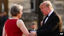 PM Inggris Theresa May (kiri) menyambut kedatangan Presiden AS Donald Trump di istana Blenheim, London, Kamis (12/7). 