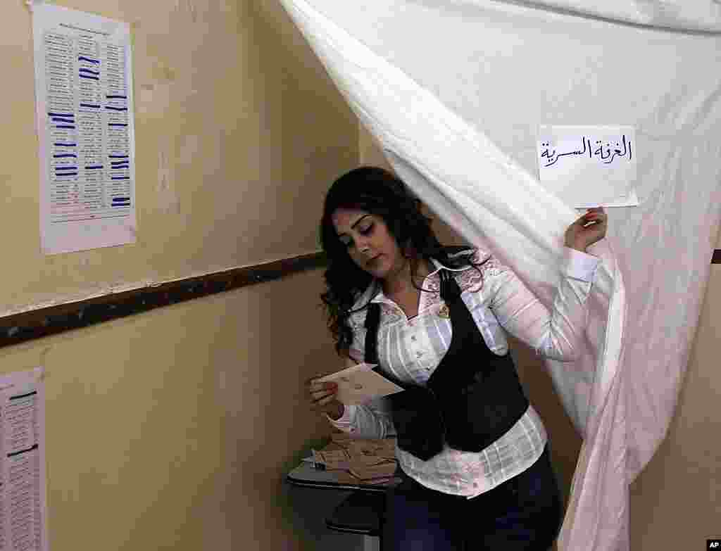 A woman comes out from behind a curtain after voting in parliamentary elections. (Reuters)