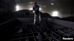 FILE - A laborer works inside a coal yard on the outskirts of Ahmedabad, India, April 6, 2017. 