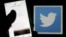FILE - A man reads tweets on his phone in front of a displayed Twitter logo in Bordeaux, southwestern France.