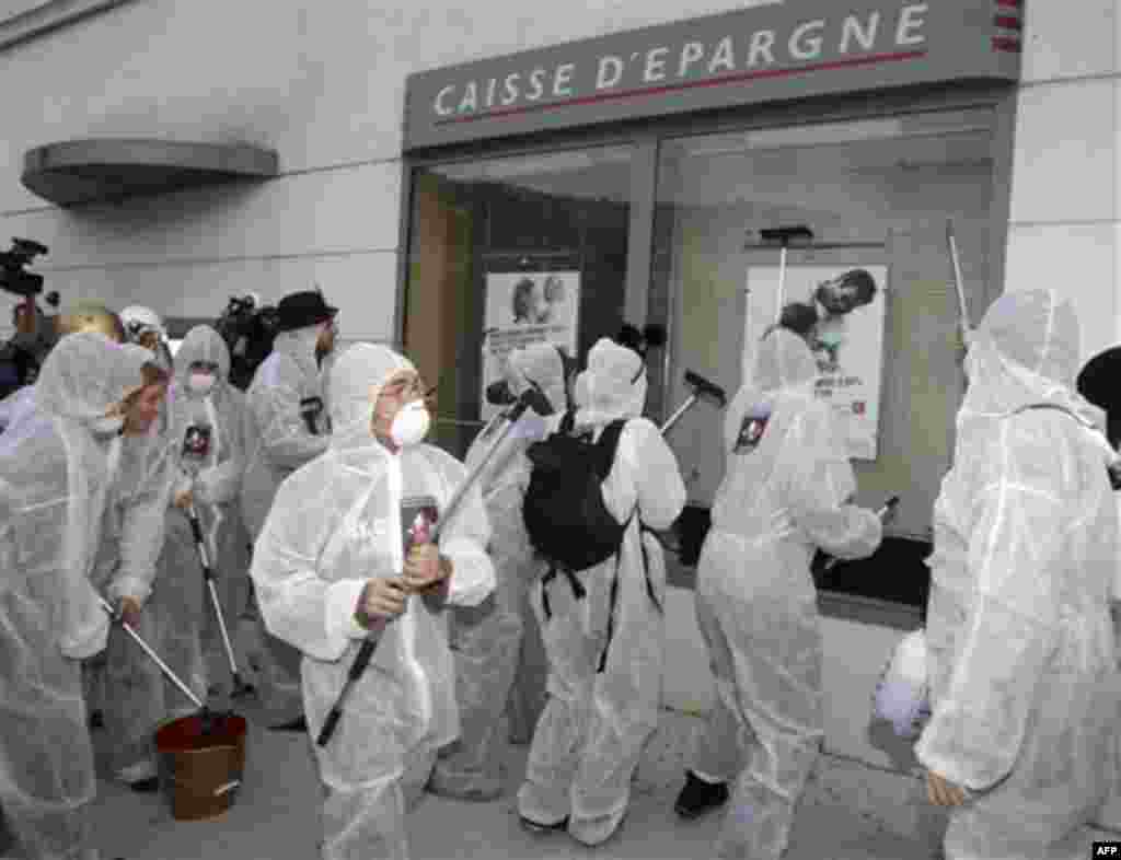 Anti-globalization members of Attac, clean the frontage of a bank in Nice, southeastern France, as they protest against the G20 summit of Cannes, Wednesday, Nov. 2, 2011.(AP Photo/Lionel Cironneau)