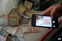 A member of the media uses his mobile phone to take pictures of belongings including banknotes of different currencies on a bed inside the flat where a suspect of New Year's Day nightclub attack was arrested during an overnight police raid, in Istanbul.