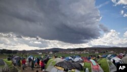 Des migrants s’apprêtent à se protéger dans leurs tentes à l’arrivée de la pluie près du poste-frontière grec d'Idomeni, le vendredi 4 mars 2016.