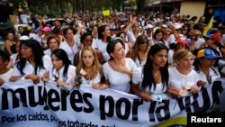 Maria Corina Machado (mano sobre el pecho) y Lilian Tintori (centro), esposa del encarcelado líder Leopoldo López, participan en una manifestación de mujeres en Caracas.