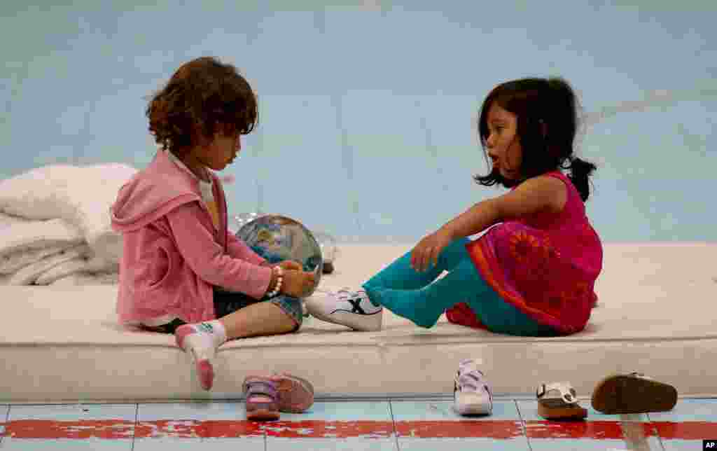 In Vienna, Austria, a sports hall is turned into a temporary refugee camp. In this image, two refugee girls sit on a mattress in the sports hall.