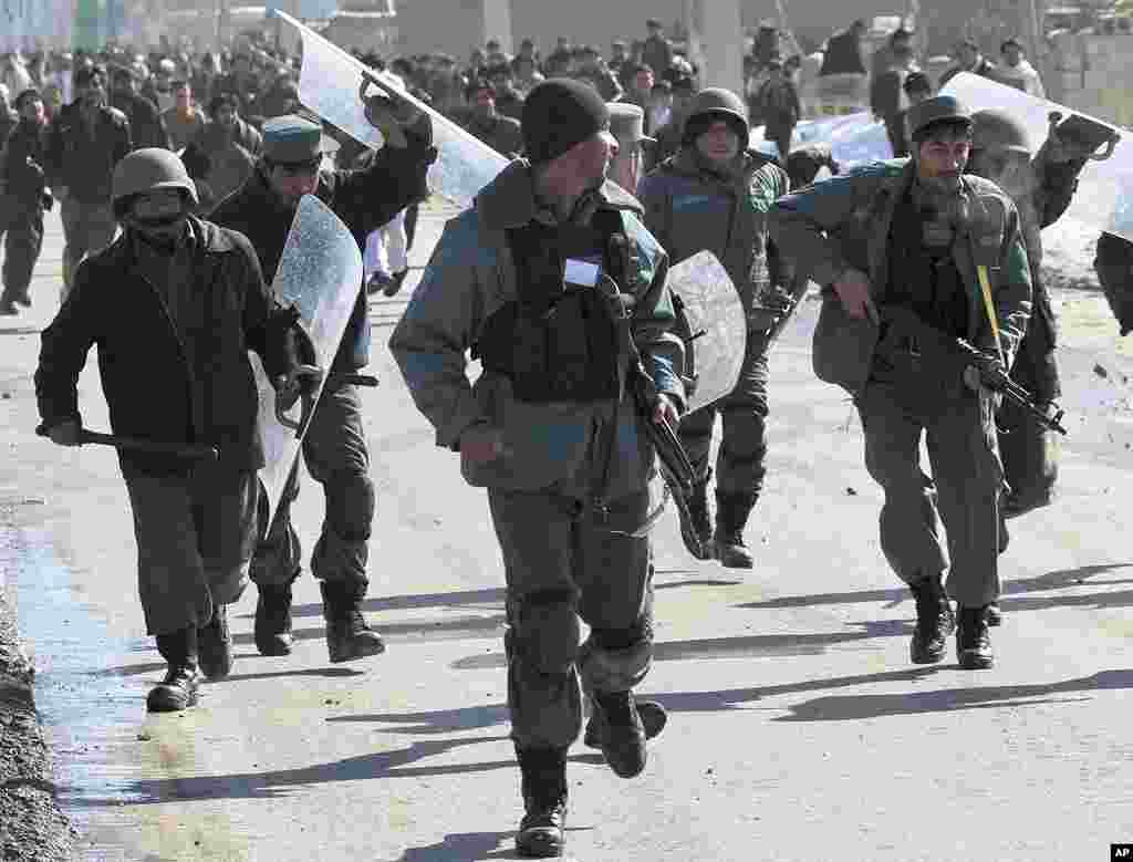 Afghan policemen run as protesters throw rocks at them near a U.S. military base in Kabul, February 22, 2012. (Reuters)
