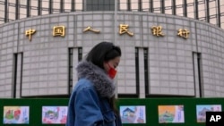 资料照：一名女子走过位于北京的中国人民银行。（2024年2月20日）