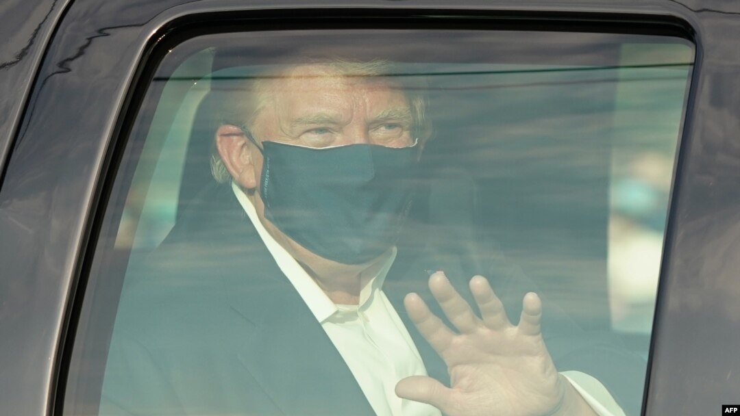Presiden AS Donald Trump melambai kepada para pendukungnya yang menunggu di luar Rumah Sakit Walter Reed Medical Center di Bethesda, Maryland hari Minggu (4/10). 