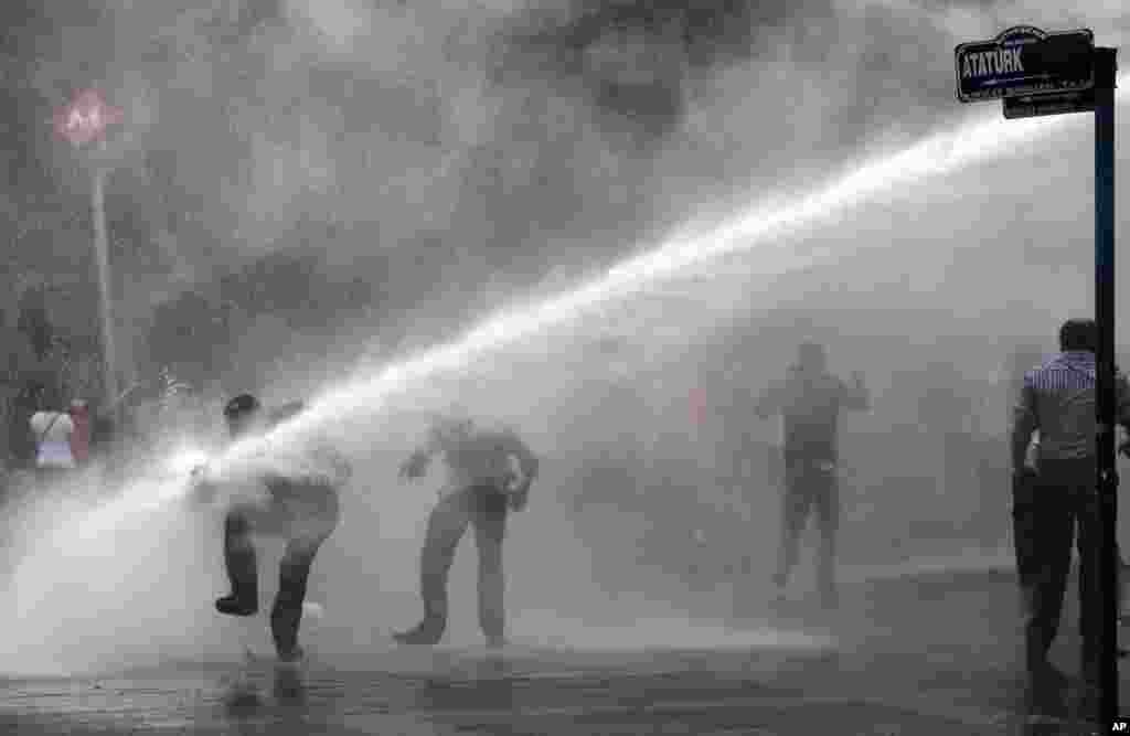 Polisi anti huru-hara menyemprotkan meriam air kepada para demonstran di Alun-Alun Kizilay, Ankara (16/6).