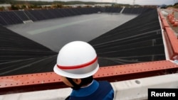 FILE - A worker stands in front of a newly installed fresh water reservoir, used to cool down nuclear reactors in case of emergencies, at Tokyo Electric Power Co.'s (TEPCO) Kashiwazaki Kariwa nuclear power plant, which is the world's biggest, in Kashiwazaki, Nov