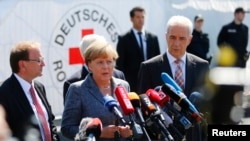 Heidenau Mayor Juergen Opitz, German Chancellor Angela Merkel and Saxony State Prime Minister Stanislaw Tillich (L to R) arrive for statements after their visit to an asylum seekers accommodation facility, Aug. 26, 2015.
