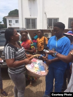 Power Women 232, a network of Sierra Leone professional women, distributes food baskets to show health care workers at Connaught Hospital in Freetown. At left is Asmaa James, the group’s vice president and studio manager of Radio Democracy. (Photo courtes