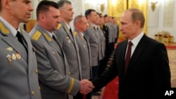 Russian President Vladimir Putin, right, shakes hands at the presentation ceremony of the top military brass in the Kremlin in Moscow, Russia, March 28, 2014