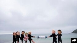 Activists wearing giant heads of the G7 leaders tussle over a giant COVID-19 vaccine syringe during an action of NGO&#39;s on Swanpool Beach in Falmouth, Cornwall, England.