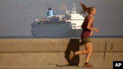 FILE - A woman is seen jogging on the Malecon as a cruise ship arrives in Havana bay, Cuba, March 19, 2015. Havana authorized, starting April 26, Cuban residents to enter and leave the island nation as passengers of cruise ships.