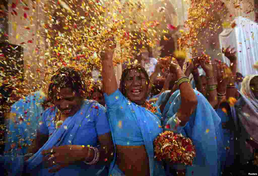 Para janda di Vrindavan, negara bagian Uttar Pradeesh melemparkan bunga dan bubuk berwarna dalam perayaan Holi atau festival warna, yang menandai awal musim semi dan dirayakan di seluruh India (24/3). (Reuters/Vivek Prakash)