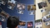 FILE - This photograph taken on Nov. 14, 2020 shows a photographer in front of pictures depicting the 2019 campus siege at the height of the city's pro-democracy protests at an exhibition in the Chinese University of Hong Kong.