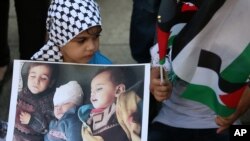 Bé gái cầm hình trẻ em Palestine bị thiệt mạng trong cuộc không kích dải Gaza của Israel trong một cuộc biểu tình chống chiến tranh tại Beirut, Libăng, ngày 21/7/2014.