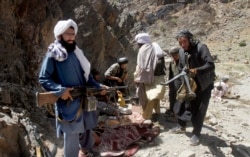 FILE - Taliban fighters prepare to guard a gathering, in Shindand district of Herat province, Afghanistan, May 27, 2016.