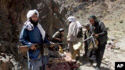 FILE - Taliban fighters stand with their weapons in Shindand district of Herat province, Afghanistan, May 27, 2016.