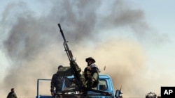 A Libyan rebel fighter sits on a truck as he fires an anti-aircraft gun on a government warplane (file photo)
