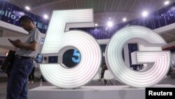 Seorang pria berdiri di sebelah tulisan 5G di sebuah pameran teknologi digita. di Kunming, Yunnan province, China, 23 Mei 2019.