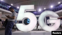A man stands next to a sign of 5G at the Tencent Global Digital Ecosystem Summit in Kunming, Yunnan province, China, May 23, 2019.