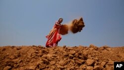 FILE - Indian woman Shanti Patel helps dig a water reservoir at the edge of an open coal mine in Sarasmal village near the industrial city of Raigarh, in Chhattisgarh state, India, April 15, 2014. While India’s rapid economic growth over the past decade has boosted the incomes and living standards of millions — mostly city-dwellers — the environmental impact has often been ignored and the rural poor have been left behind. 