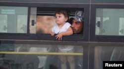 A Syrian man with a child is shown in a bus in Jroud Arsal, Lebanon, Aug. 2, 2017. 
