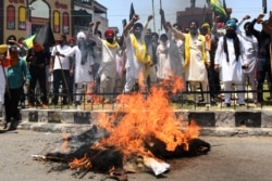 Para petani membawa bendera hitam sambil meneriakkan slogan-slogan saat mereka membakar patung Perdana Menteri India Narendra Modi, ketua Reliance Industries Ltd Mukesh Ambani dan Ketua Grup Adani Gautam Adani, dalam memperingati 'Hari Hitam' yang menandai enam bulan protes reformasi pertanian di Amritsar, 26 Mei 2021. (AFP)