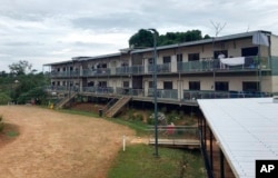 In this July 17, 2018, photo a man stands on a balcony at the East Lorengau Refugee Transit Center on Manus Island, Papua New Guinea.
