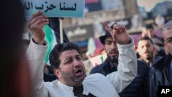 شهروند سوری در جنوب کشور در مرز با اسرائیل با نوشته‌ای بالای سرش: «ما حزب‌الله نیستیم» (آرشیو)