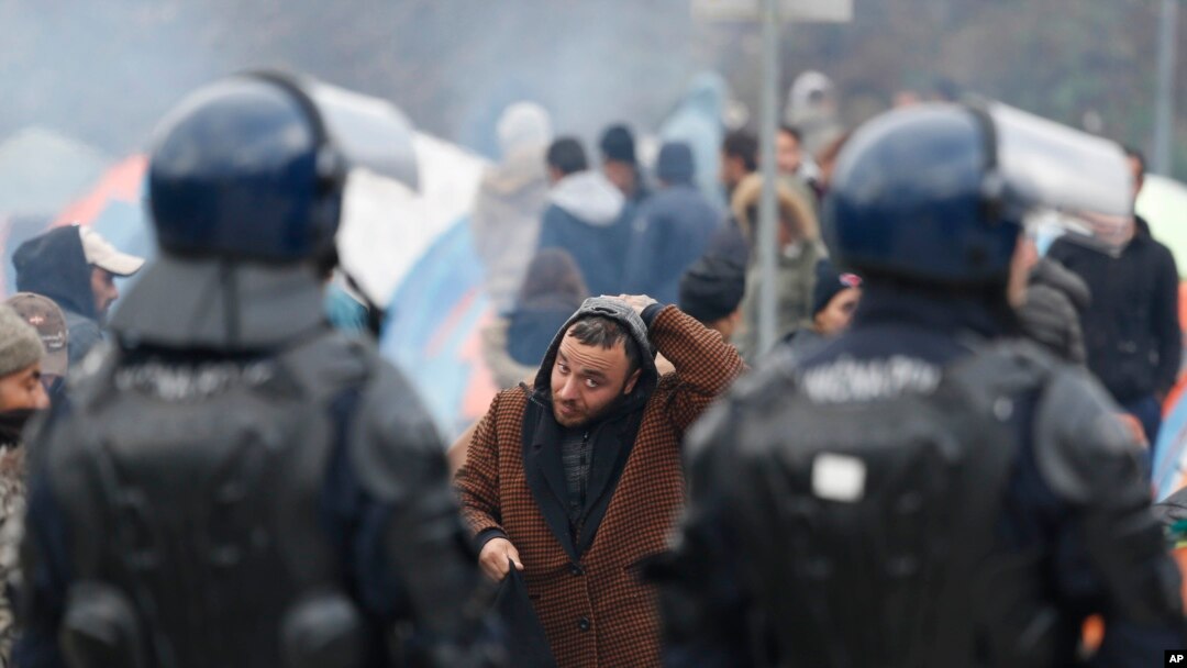 Seorang migran membetulkan penutup kepalanya saat berjalan di depan barisan polisi Bosnia di persimpangan perbatasan Maljevac, Bosnia, 26 Oktober 2018. (Foto: dok).
