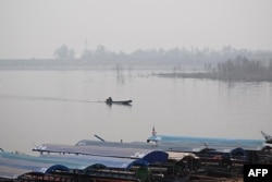 A man steers a boat on a lake amidst high air pollution at the Srilanna National Park in the northern Thai province of Chiang Mai on March 16, 2024. (Photo by Lillian SUWANRUMPHA / AFP)