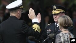 Retiring Joint Chiefs Chairman Adm. Mike Mullen, left, administers the Oath of Office for the new Joint Chiefs Chairman Gen. Martin Dempsey, during a 'Change of Office' ceremony at Ft. Myer in Arlington, Virginia, September 30, 2011. Holding the bible is 