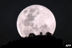 The moon rises over Kadam mountain in Nakapiripirit town, northeastern Uganda, Jan. 31, 2018, during the lunar phenomenon referred to as the "super blue blood moon".