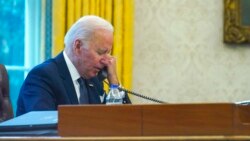 In this image made through a window, President Joe Biden talks on the phone with Ukrainian President Volodymyr Zelenskiy from the Oval Office of the White House in Washington, Dec. 9, 2021.