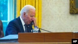 FILE - In this image taken through a window, U.S. President Joe Biden talks on the phone in the Oval Office of the White House in Washington, Dec. 9, 2021.