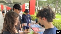 Des étudiants distribuent des brochures aux jeunes électeurs à la Florida Atlantic University, le jeudi 11 avril 2024, à Boca Raton, en Floride. (AP Photo/Cody Jackson)