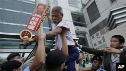 A pro-democracy protester holding the picture of the jailed Chinese dissident Liu Xiaobo, tries to climb across the police line during a demonstration at the China Liaison Office in Hong Kong, Nov 11, 2010 (file photo)