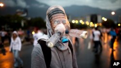 Protester in gas mask made from plastic water bottles helps block highway to airport, Caracas, Venezuela, Feb. 18, 2014.