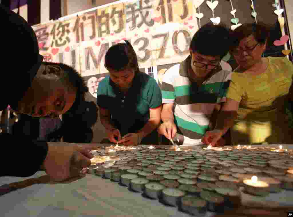 People light candles during a ceremony for those on board flight MH370 in Kuala Lumpur, March 30, 2014.