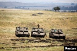 An Israeli soldier stands on a tank as another jumps off it near the Israeli side of the border with Syria in the Israeli-occupied Golan Heights, Israel, May 9, 2018.