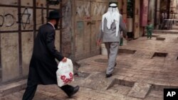 FILE - Аn Orthodox Jew walks behind a Palestinian man on a street in the walled Old City of Jerusalem.