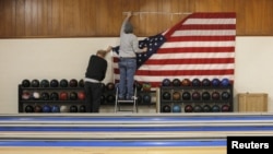 Workers take down a U.S. flag following a campaign stop by Democratic presidential candidate Hillary Clinton at the Family Fun Center in Adel, Iowa, Jan. 27, 2016.